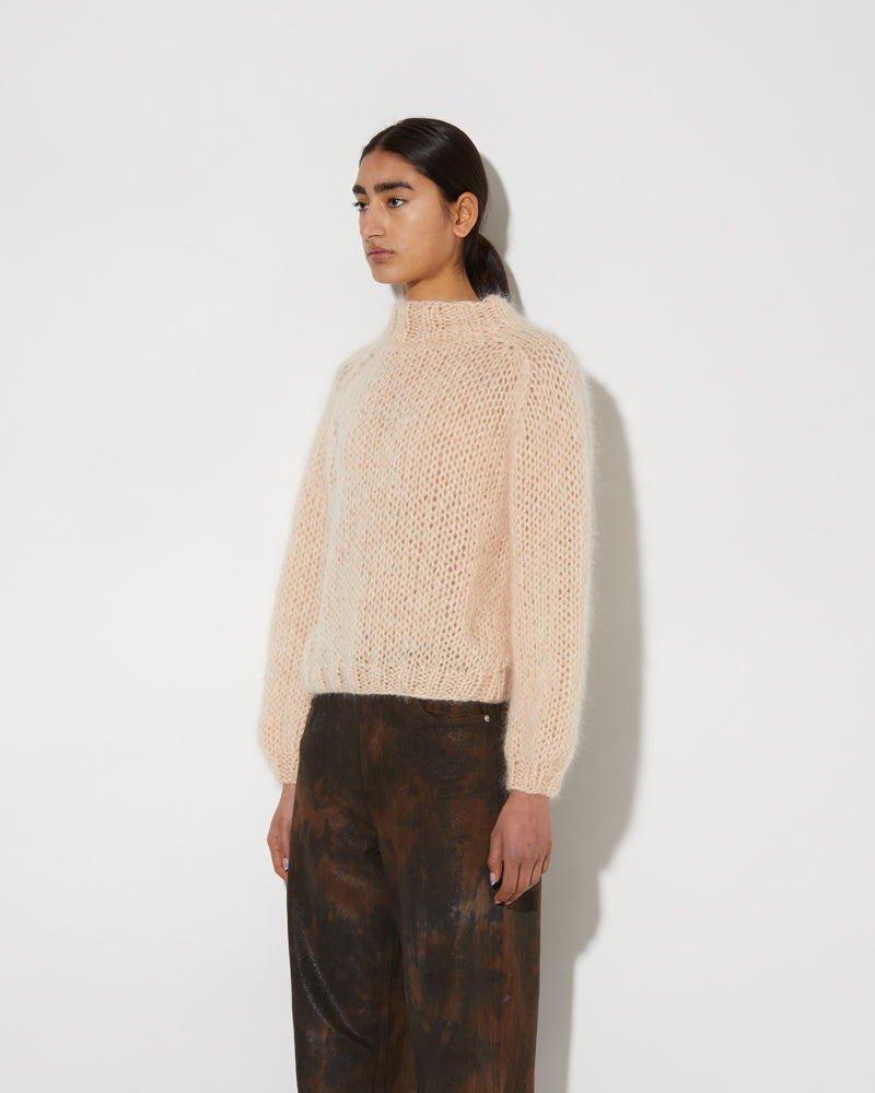 Model wearing a soft mohair textured pullover with airy knit structure and relaxed fit in a light neutral tone