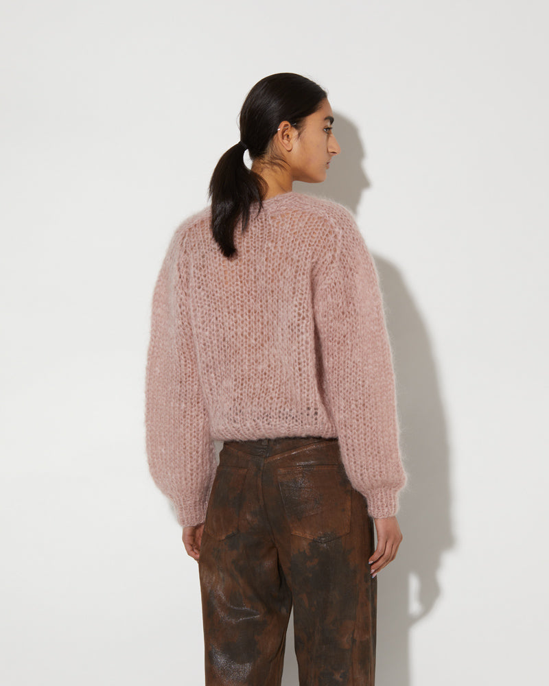 Model wearing a mohair V-neck pullover with soft textured knit and relaxed slightly cropped fit in a muted pink tone