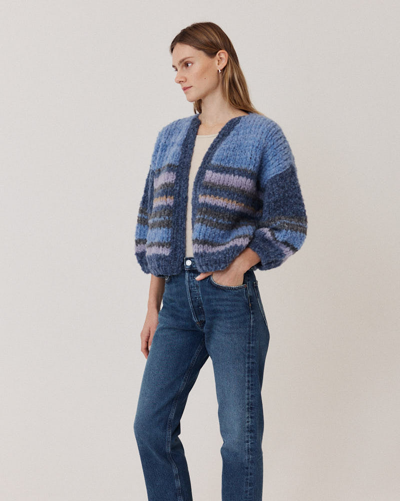Model wearing hand-knitted alpaca cardigan with stripes in blue tones