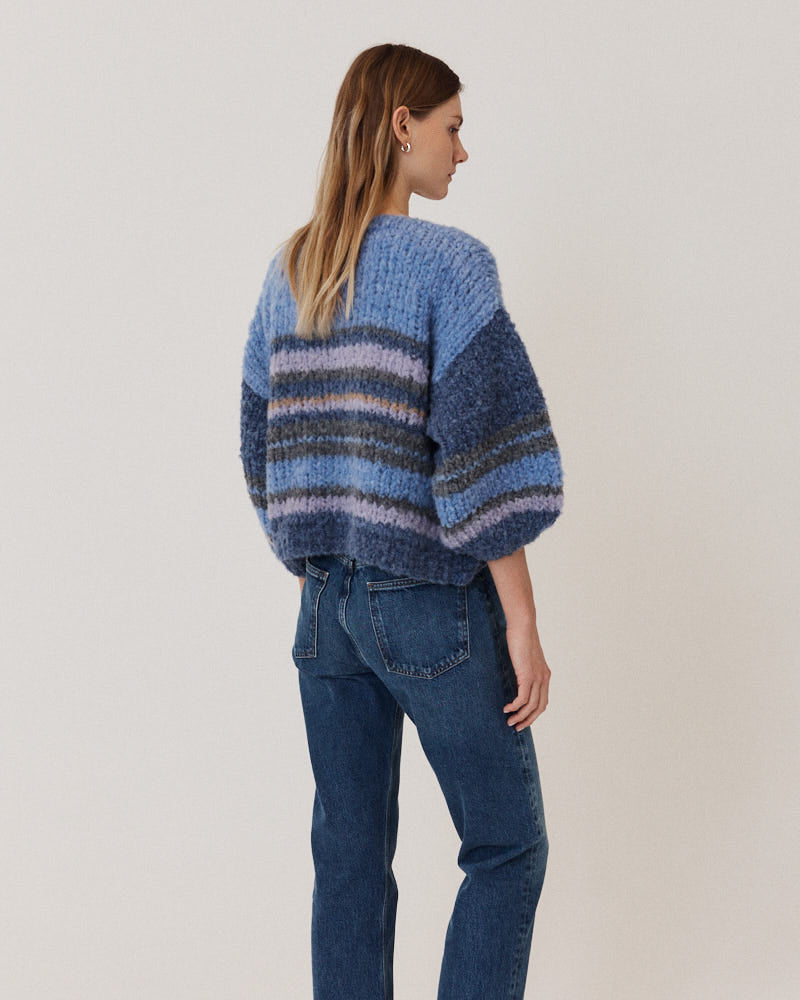 Model wearing hand-knitted alpaca cardigan with stripes in blue tones