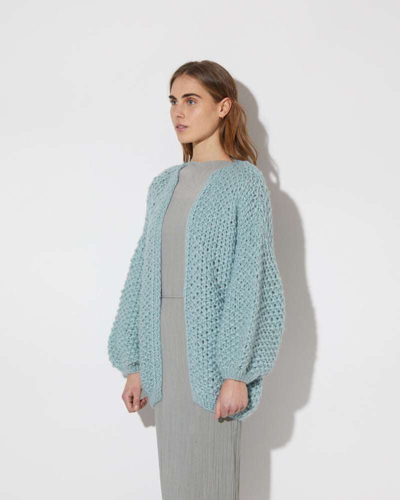 View from the side of model wearing the new in Alpaca Pearl Pattern Cardigan - long in the color 'Steel Green 2187'