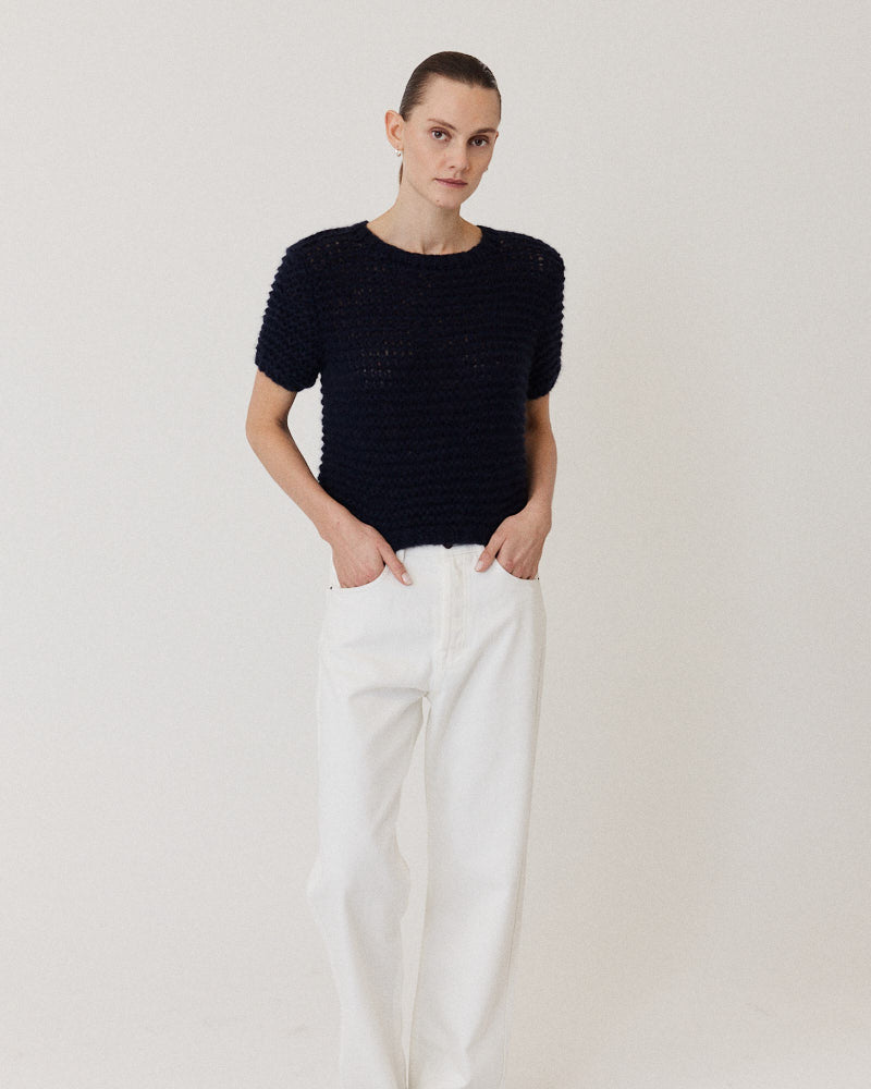 Model wearing hand knitted cashmere sweater with short sleeves in navy