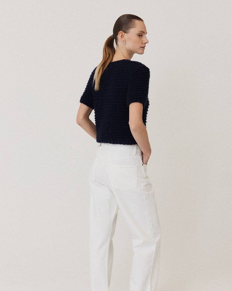 Model wearing hand knitted cashmere sweater with short sleeves in navy