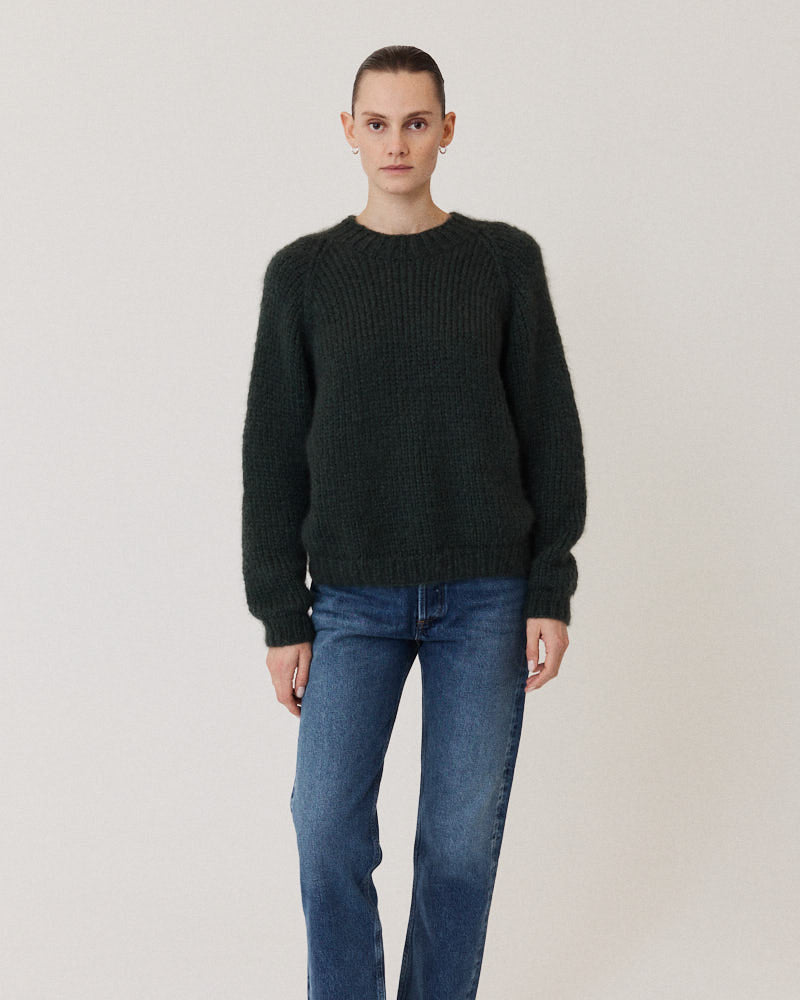 Model wearing a dark green sweater knitted of cashmere