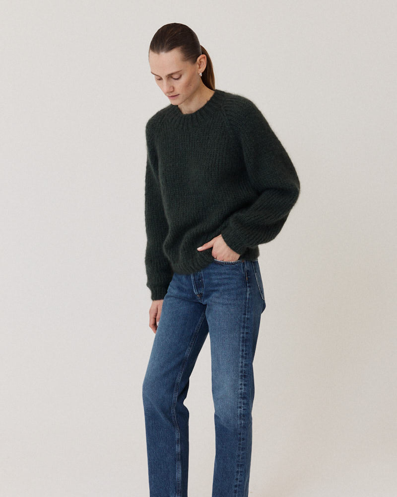 Model wearing a dark green sweater knitted of cashmere
