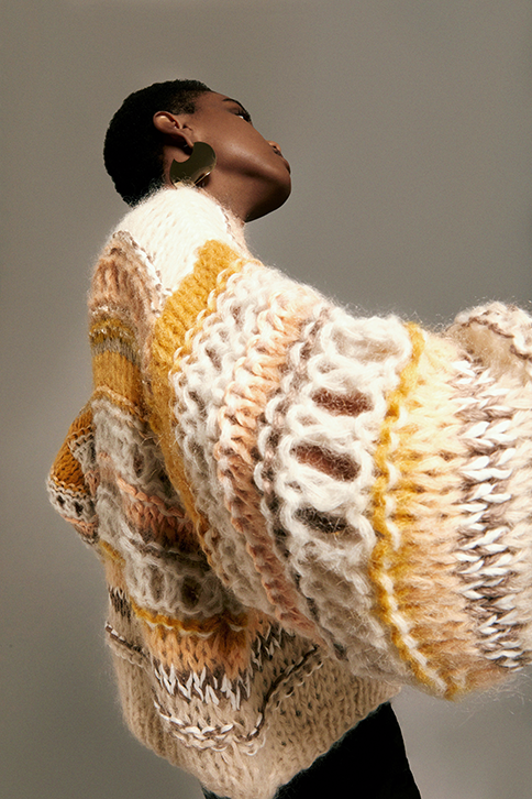 Side shot of Model wearing   the Texture Galore Bomber Cardigan in sand. 