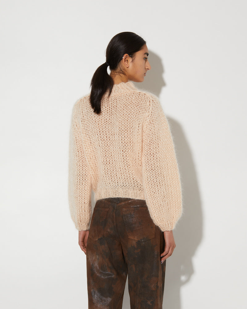 Model wearing a soft mohair textured pullover with airy knit structure and relaxed fit in a light neutral tone