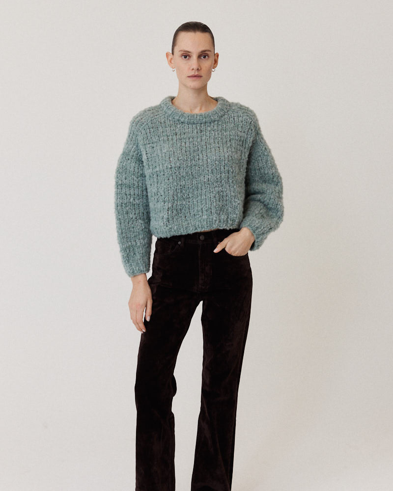 Model wearing boxy hand-knitted sweater made of a wool alpaca blend in a pastel green