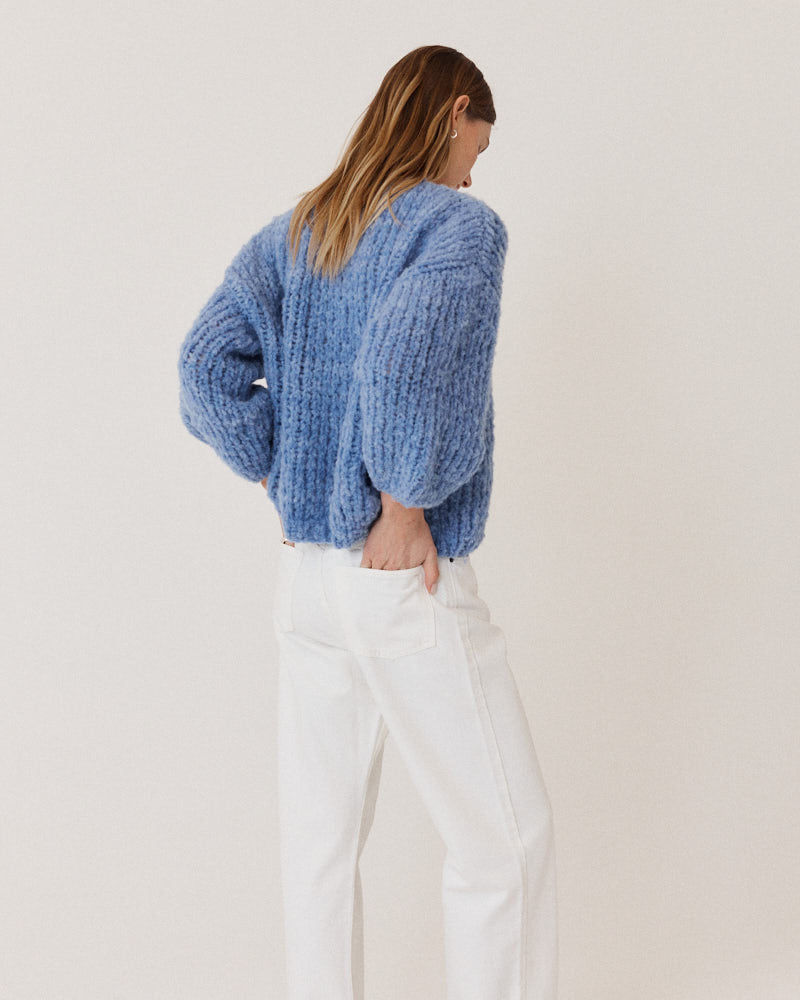 Model wearing structured hand-knitted alpaca cardigan in light blue