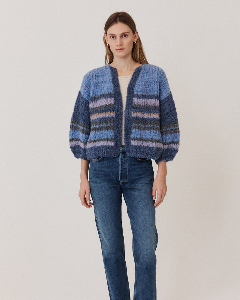 Model wearing hand-knitted alpaca cardigan with stripes in blue tones