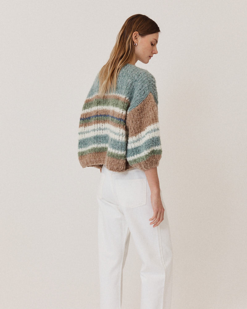 Model wearing hand-knitted alpaca cardigan with stripes in green tones
