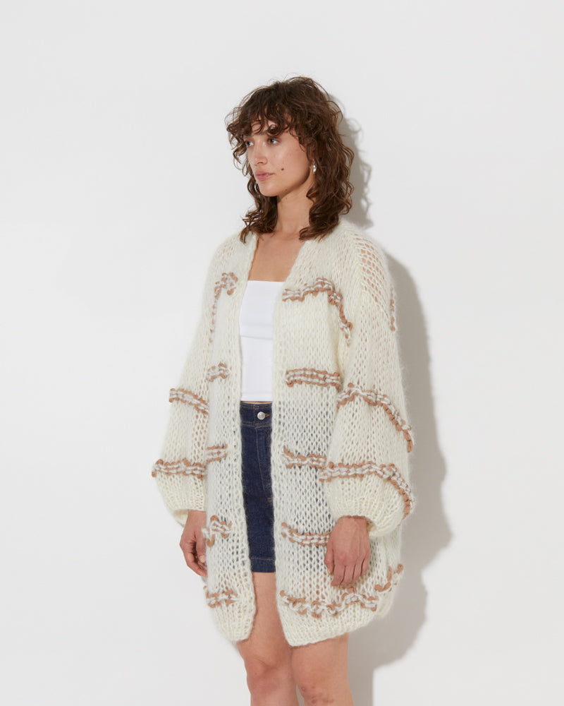 model wearing the wavy spring oversized cotton cardigan in creme and summer tan. Shot from the side